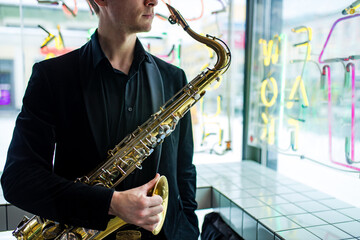 saxophone in hands close-up man in black outfit