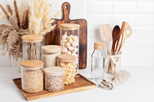 Assortment Of Grains, Cereals And Pasta In Glass Jars And Kitchen Utensils On Wooden Table. Healthy Balanced Food, Sustainable Lifestyle, Zero Waste Storage, Eco Friendly Idea