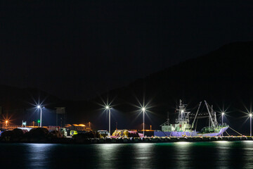 Ship light reflected on the surface of the water at the harbor at night