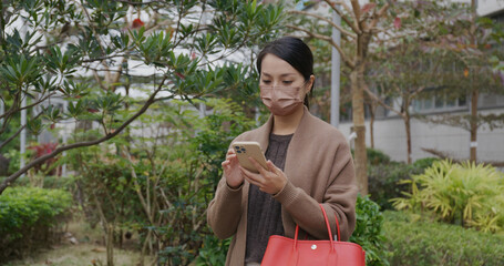 Poster - Woman wear face mask and use of mobile phone at park