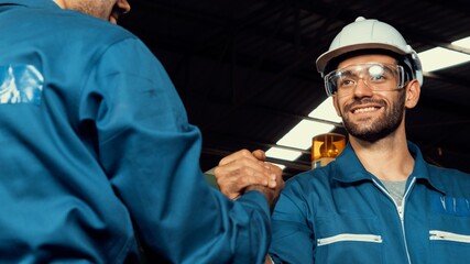 Two skillful factory engineer or worker showing teamwork and partnership . Industrial people and manufacturing labor concept .