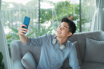 Wall Mural - Young handsome man taking selfie wearing wireless headphones listening music