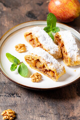 Wall Mural - homemade fragrant strudel with apples and cinnamon on a plate on a wooden background with space for text