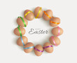 Happy Easter. Chicken eggs, wrapped in bright multicolored satin ribbons, are arranged in the form of a round wreath on a white background. Use for holiday design, banner, cards, social media posts.