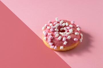 Pink donut with marshmallow topping on two colour background .Sweet minimalist food image. Modern concept.