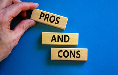 Pros and cons symbol. Wooden blocks with words 'Pros and cons'. Beautiful blue background, businessman hand. Business, pros and cons concept, copy space.