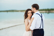 © omelnickiy - young couple a guy in black breeches and a girl in a pink dress are walking along the white sand