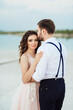 © omelnickiy - young couple a guy in black breeches and a girl in a pink dress are walking along the white sand
