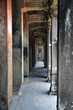 Empty corridor inside Angkor Wat complex with crafted Buddha on columns