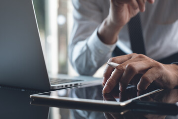 Poster - Businessman using digital tablet and working on laptop computer, thinking about work project at office