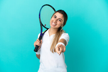 Young woman tennis player isolated on blue background pointing front with happy expression