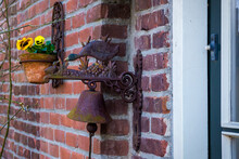 Vintage Door Bell With Metal Duck And Flower Pot On The Red Brick Wall
