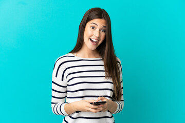 Wall Mural - Teenager Brazilian girl over isolated blue background surprised and sending a message