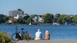 hamburg alster lakeview on a sunny day with to people in the front sitting near by the water with a parking bike, germany