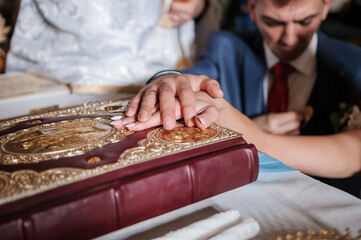 Hands of the bride and groom on the Bible. Church wedding ceremony