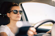 © Julien - Jeune femme conduit une voiture, en été, avec des lunettes de soleil