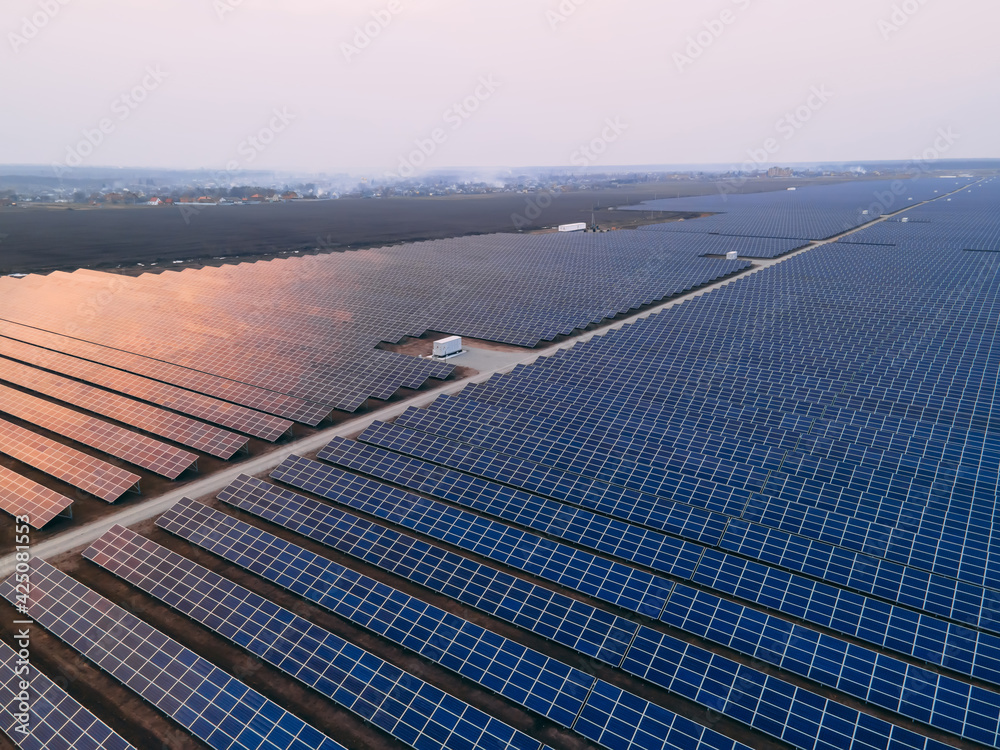 Aerial drone view into large solar panels at a solar farm at bright ...
