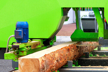 Powerful electric saw cuts large logs, close-up.