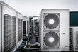 Square air-conditioning units on the roof with round fan grills. In the background gradually receding other units and parts of ventilation system which are out of focus. Sky is uniformly gray.