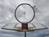 A plane flying over the basketball hoop.