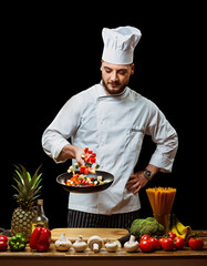 Handsome Italian chef tosses chopped vegetables in a frying pan