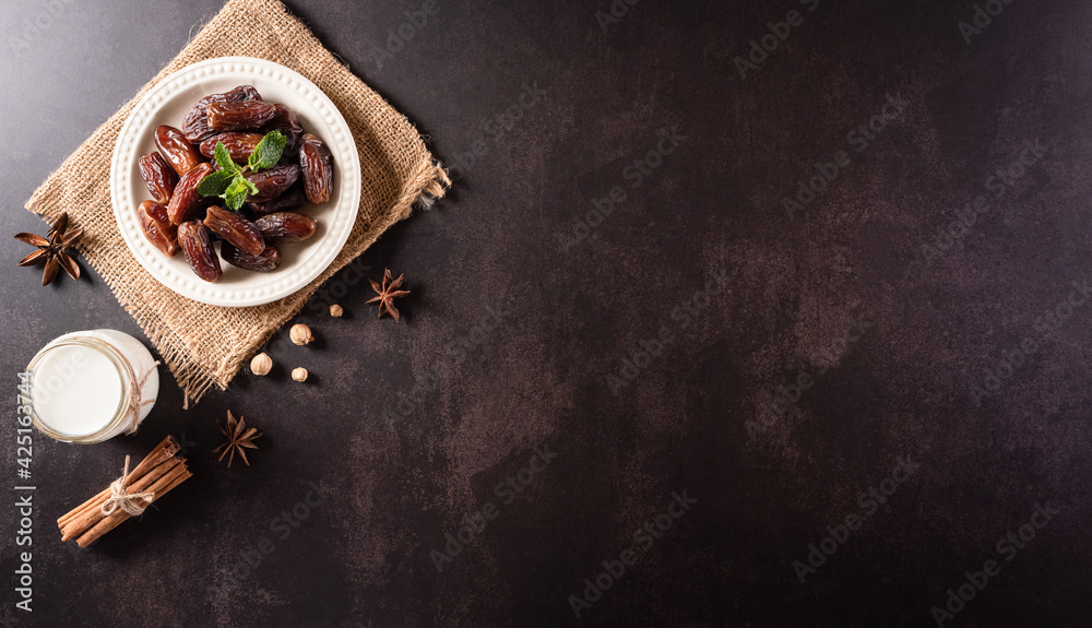 Table top view image of decoration Ramadan Kareem, dates fruit and and milk on dark stone background. Flat lay with copy space. - obrazy, fototapety, plakaty 
