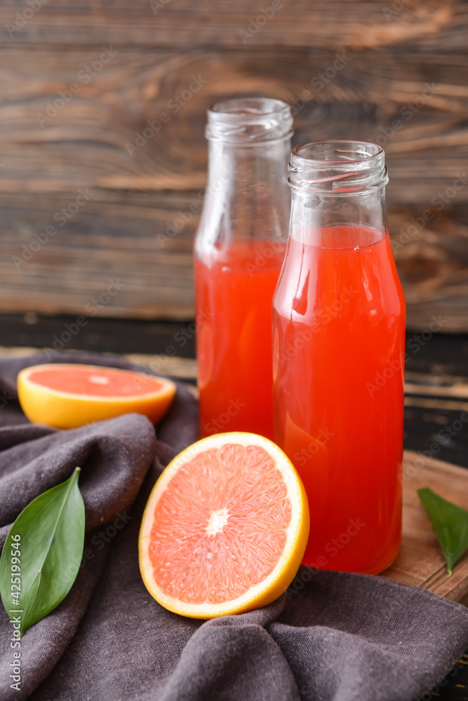 Bottles of grapefruit juice on wooden background