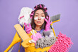 Photo of serious young Asian woman applies patches under eyes has scrupulous look cares about cleanliness and purity busy doing housework isolated over purple background. Housecleaning concept