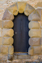 Old Ancient Black Wooden Door Framed With Big Sandstone Archway