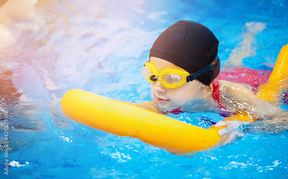 Little kid girl with glasses learning to swim with pool noodle - obrazy, fototapety, plakaty 