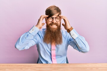 Canvas Print - Young irish redhead man wearing business shirt and tie sitting on the table with hand on head, headache because stress. suffering migraine.