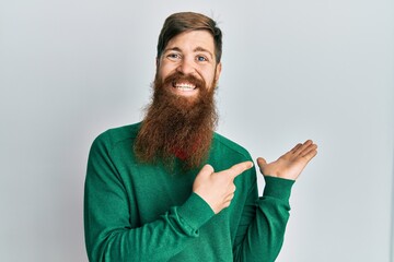 Sticker - Redhead man with long beard wearing casual clothes amazed and smiling to the camera while presenting with hand and pointing with finger.