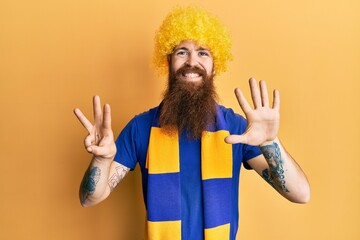 Canvas Print - Redhead man with long beard football hooligan cheering game wearing funny wig showing and pointing up with fingers number eight while smiling confident and happy.