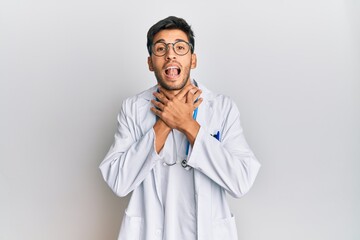 Young handsome man wearing doctor uniform and stethoscope shouting and suffocate because painful strangle. health problem. asphyxiate and suicide concept.