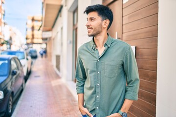 Young latin man smiling happy walking at the city.