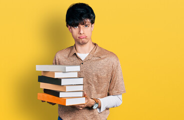 Sticker - Handsome hipster young man holding a pile of books depressed and worry for distress, crying angry and afraid. sad expression.