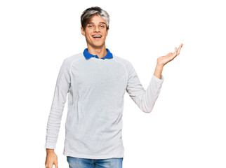 Young hispanic man wearing casual clothes smiling cheerful presenting and pointing with palm of hand looking at the camera.