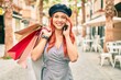 © Krakenimages.com - Young redhead girl holding shopping bags and talking on the smartphone at the city.