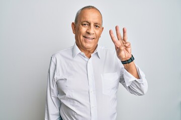 Wall Mural - Handsome senior man wearing casual white shirt showing and pointing up with fingers number three while smiling confident and happy.