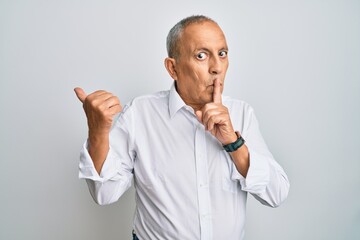 Wall Mural - Handsome senior man wearing casual white shirt asking to be quiet with finger on lips pointing with hand to the side. silence and secret concept.