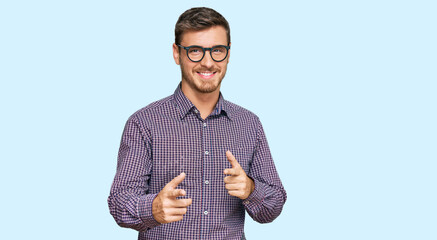 Handsome caucasian man wearing casual clothes and glasses pointing fingers to camera with happy and funny face. good energy and vibes.