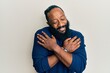 © Krakenimages.com - Young african american man wearing casual clothes hugging oneself happy and positive, smiling confident. self love and self care