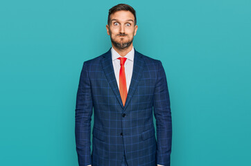 Poster - Handsome man with beard wearing business suit and tie puffing cheeks with funny face. mouth inflated with air, crazy expression.