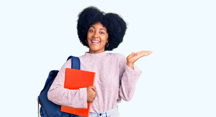 Sticker - Young african american girl wearing student backpack holding book celebrating victory with happy smile and winner expression with raised hands