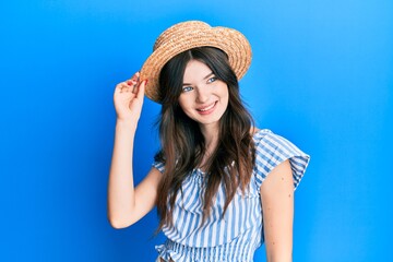 Wall Mural - Young beautiful caucasian girl wearing summer hat looking to side, relax profile pose with natural face and confident smile.