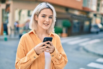 Sticker - Young blonde girl smiling happy using smartphone at the city.