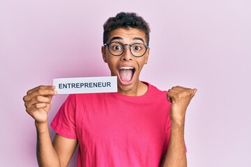 Poster - Young handsome african american man holding entrepreneur paper pointing thumb up to the side smiling happy with open mouth