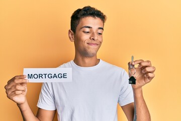 Canvas Print - Young handsome african american man holding paper with mortgage word and house keys smiling looking to the side and staring away thinking.