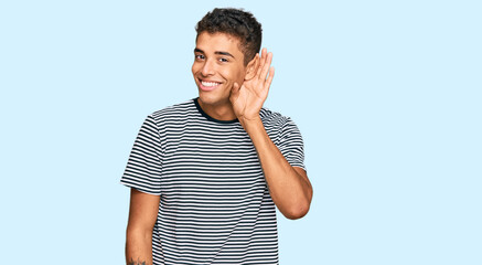 Sticker - Young handsome african american man wearing casual clothes smiling with hand over ear listening an hearing to rumor or gossip. deafness concept.