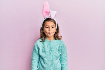 Little beautiful girl wearing cute easter bunny ears making fish face with lips, crazy and comical gesture. funny expression.